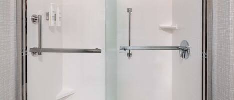 A modern bathroom with a glass shower enclosure, a toilet, and a sink with a towel rack.