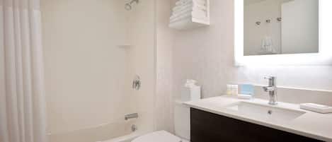 Une salle de bain moderne équipée d’une baignoire, de toilettes et d’un meuble-lavabo avec un miroir.