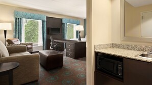 A hotel room with a sofa, a desk, a chair, a television, a microwave, and a sink. - Hampton Inn & Suites Bluffton-Sun City (Bluffton)