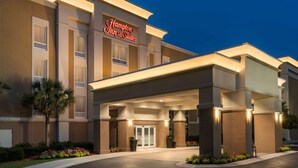 A Hampton Inn & Suites hotel with a modern facade, large windows, and a well-lit entrance. - Hampton Inn & Suites Bluffton-Sun City (Bluffton)