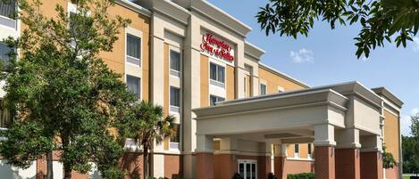 A hotel with a modern facade, a covered entrance, and landscaped gardens.