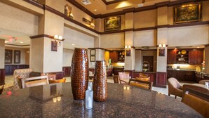 A spacious hotel lobby with a granite reception desk, seating area, and a kitchen in the background. - Hampton Inn & Suites Stillwater (Stillwater)