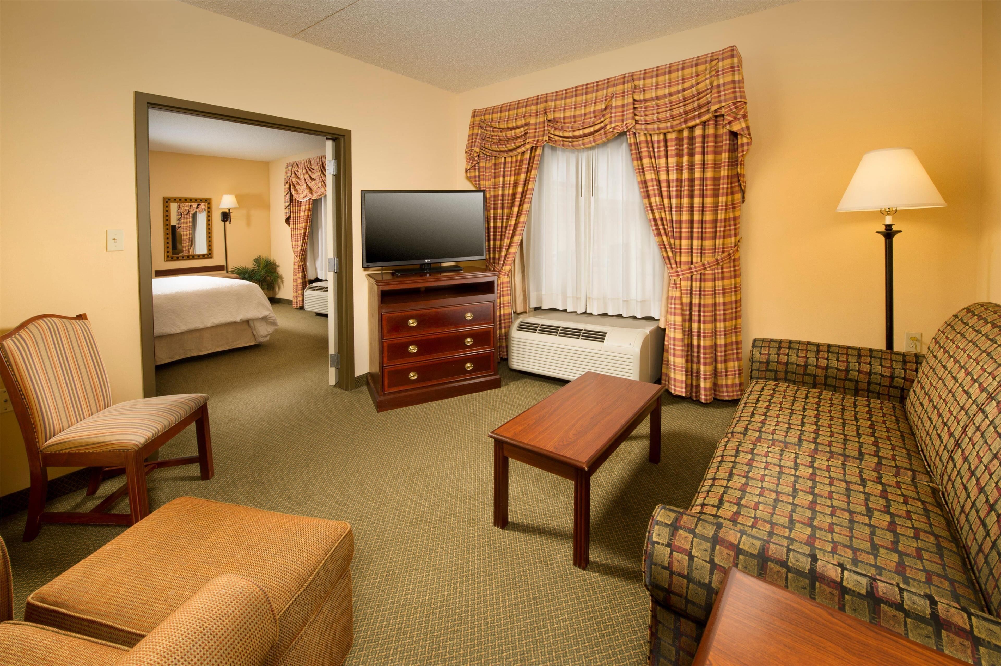 Une chambre d’hôtel équipée d’un lit, d’une télévision, d’un canapé, d’une chaise, d’une table et d’une lampe.
