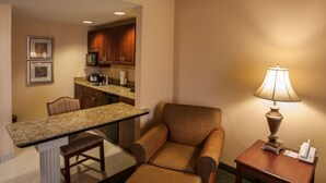 A hotel room with a dining area, a sofa, a lamp, and a small table. - Hampton Inn & Suites Stillwater (Stillwater)
