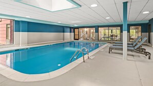 An indoor swimming pool with clear blue water, a sunroof, and lounge chairs. - Hampton Inn Elkton (Elkton)