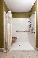 A shower area with a grab bar, a showerhead, and a curtain.