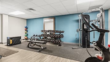 A gym with exercise equipment, a mirror, and a rack of dumbbells.