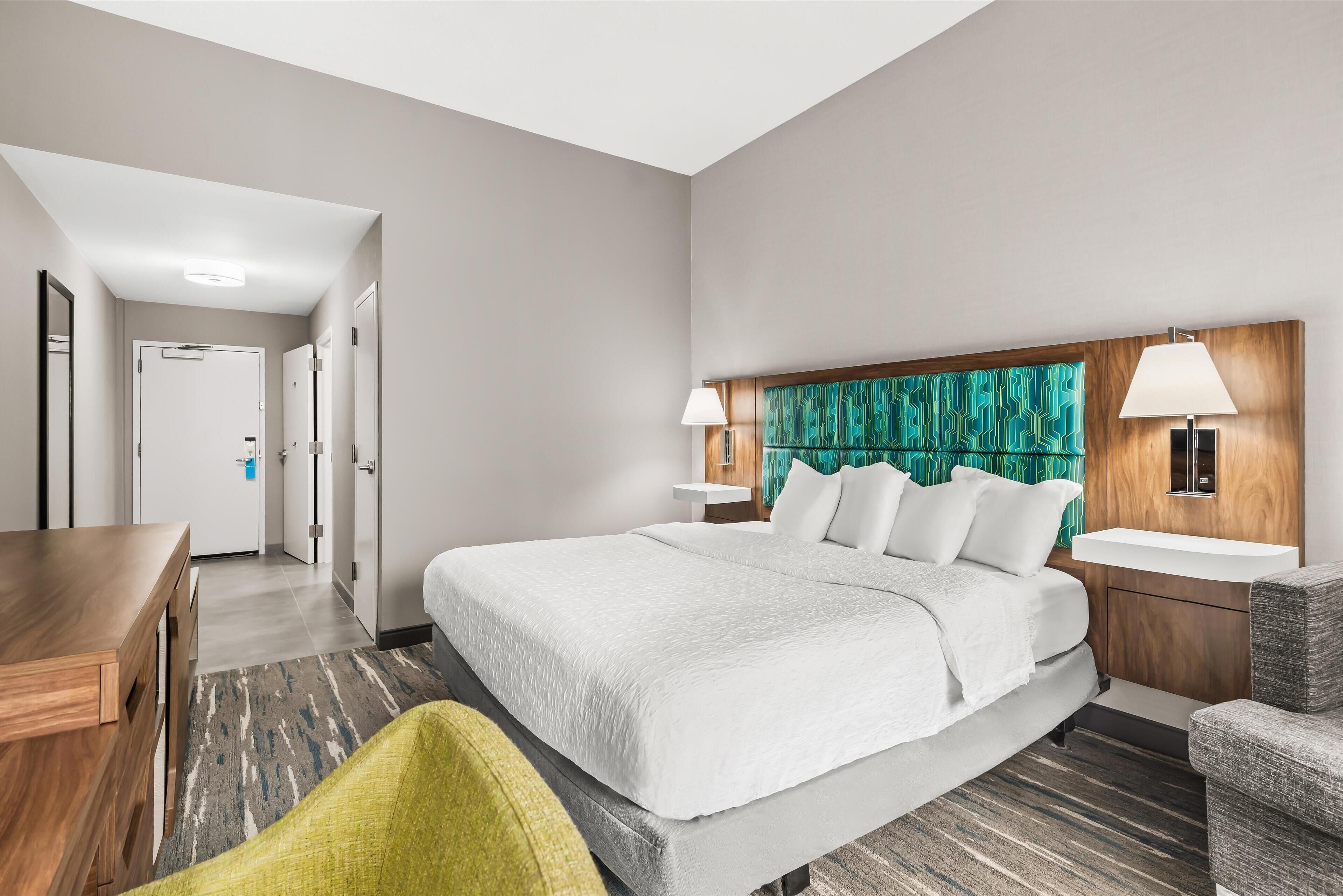 A hotel room with a large bed, bedside tables, a desk, and a chair.