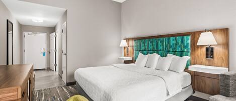 A hotel room with a large bed, bedside tables, a desk, and a chair.