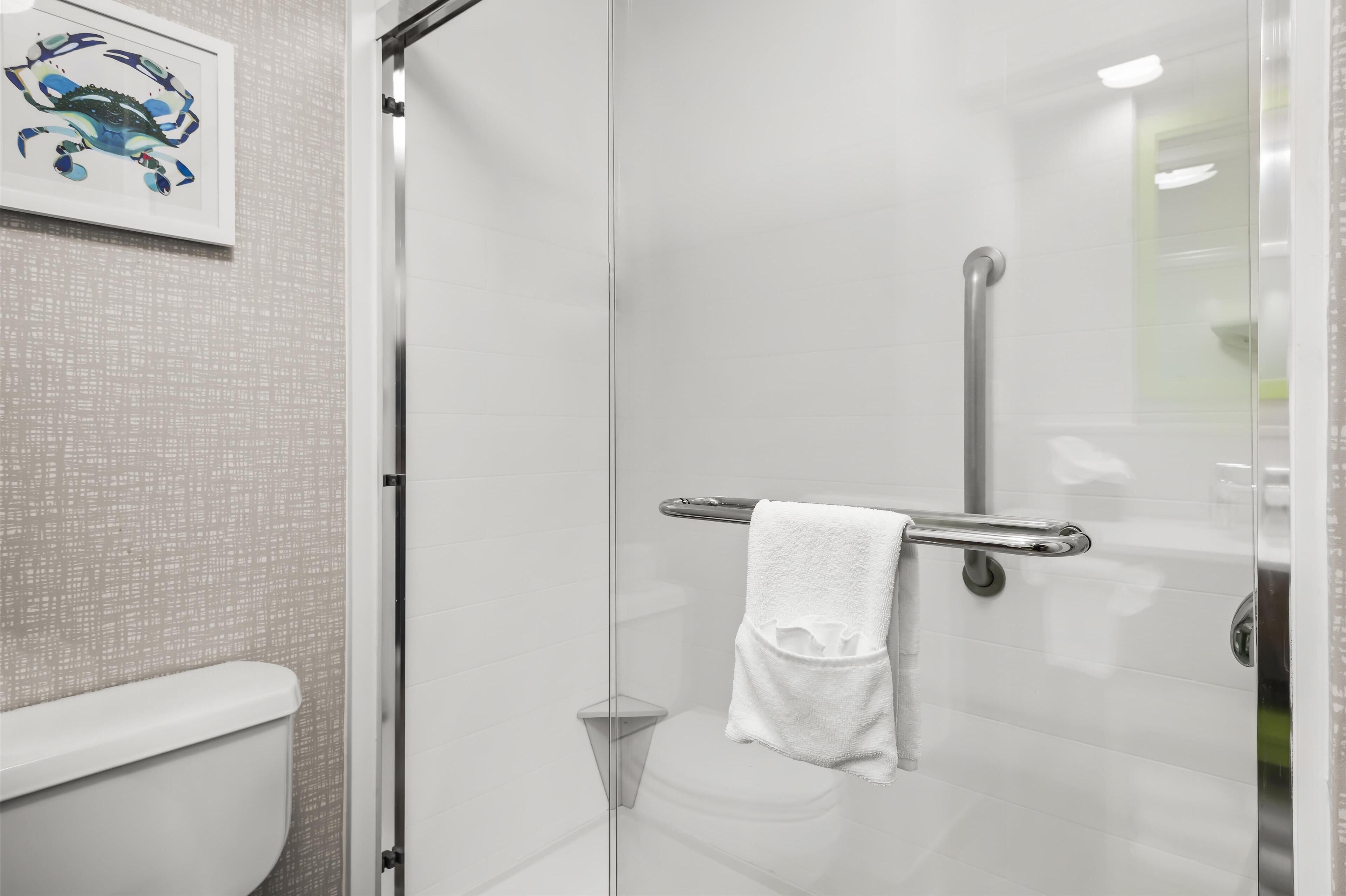 A modern bathroom with a glass shower enclosure, a white toilet, and a towel rack with a white towel.