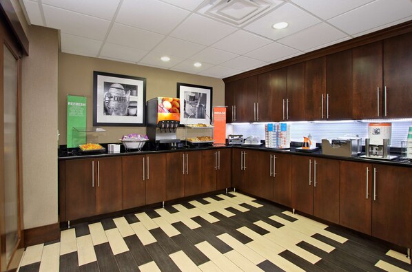 A hotel kitchen with wooden cabinets, a patterned floor, and various appliances.