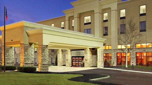 Un hotel con entrada cubierta, fachada de piedra y varias ventanas.