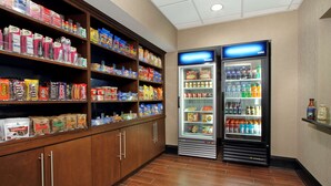 Un espacio autoservicio con aperitivos y bebidas, estantes llenos de bocadillos, bebidas embotelladas y una sección refrigerada.