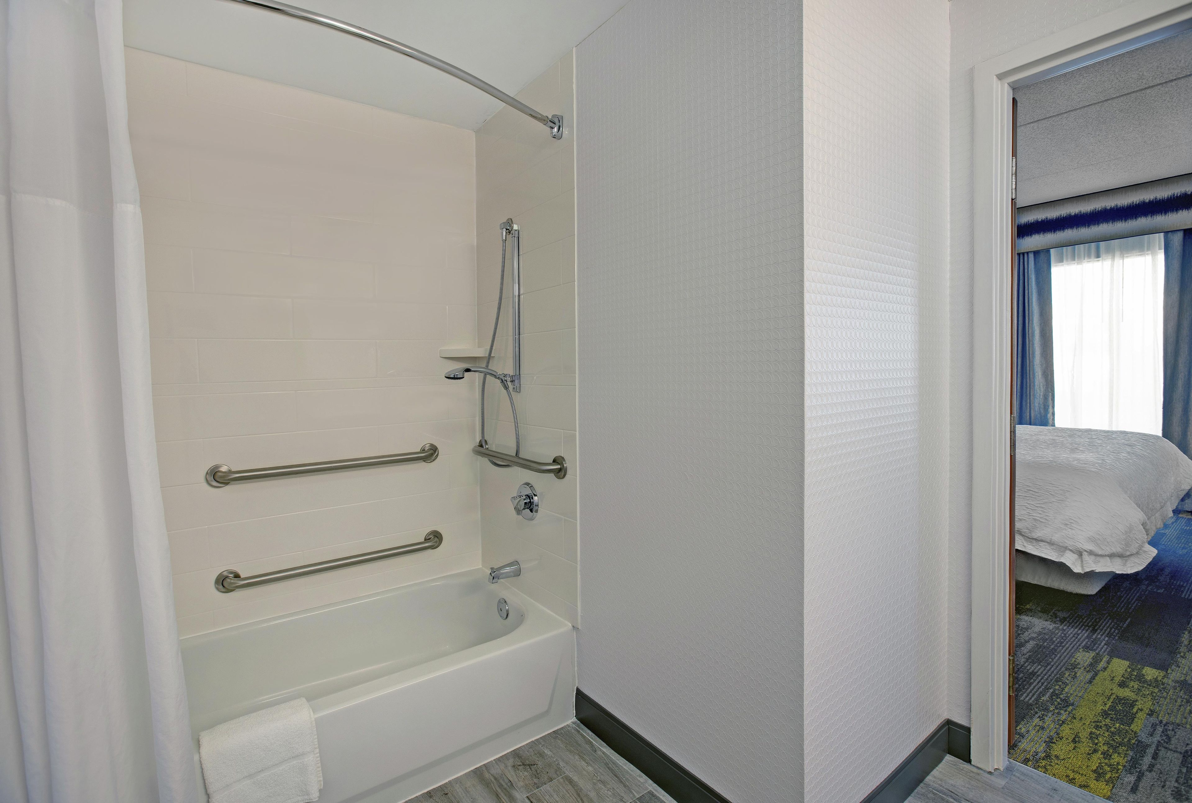 Une salle de bain moderne équipée d’une baignoire, de barres d’appui et d’une douche.
