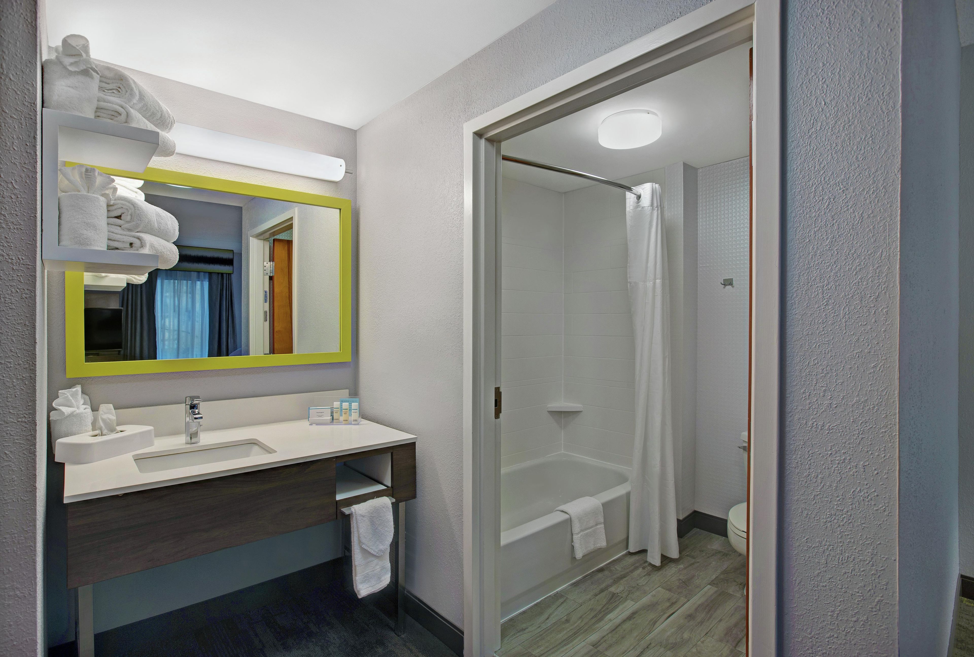 A modern bathroom with a sink, mirror, and shower.