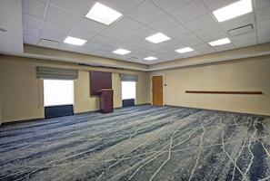 A conference room with a carpeted floor, a podium, and a door. - Hampton Inn & Suites Augusta West (Augusta)
