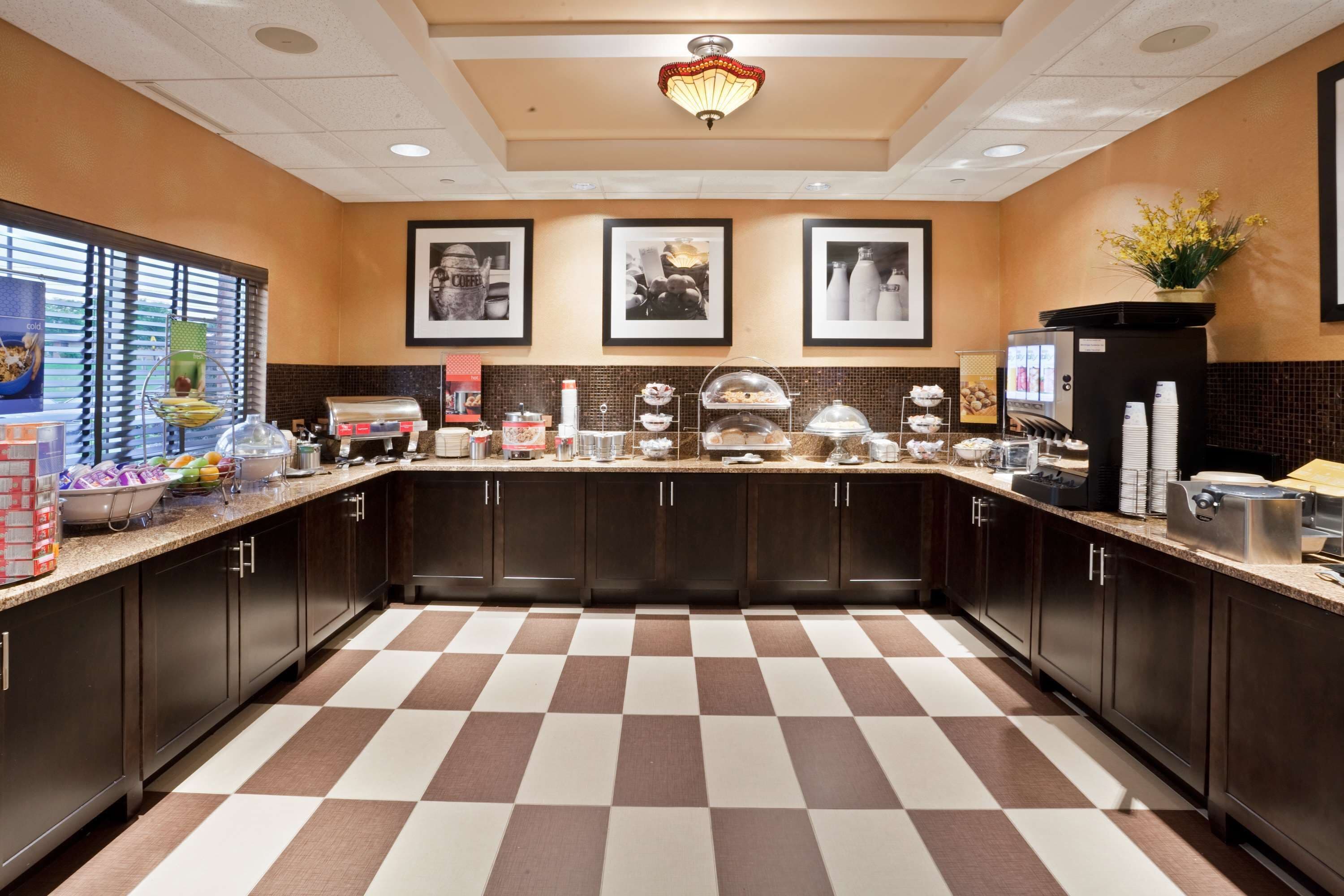 A modern kitchen with checkered flooring, dark cabinets, and various appliances.