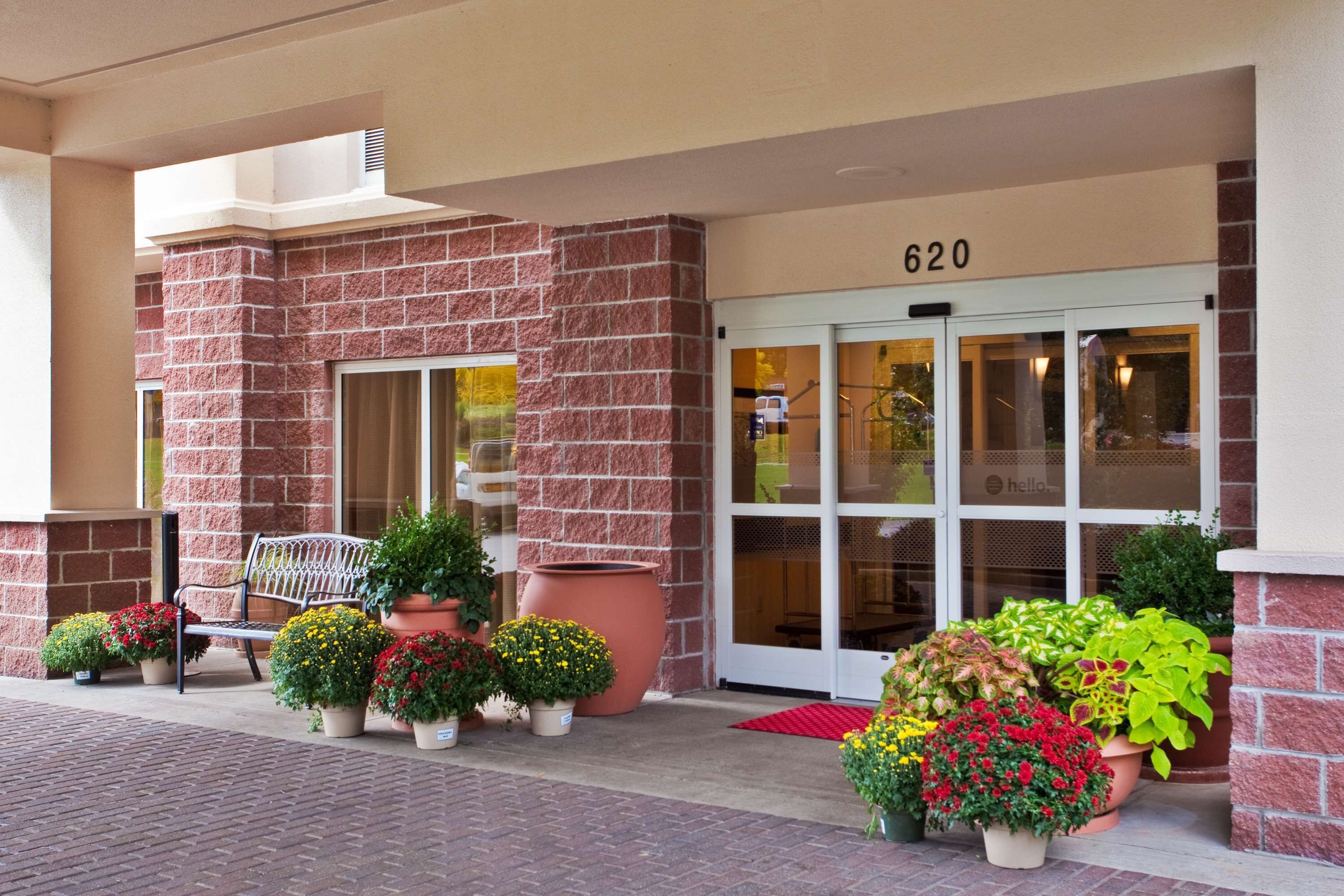 A hotel entrance with a brick facade, numbered 620, and a variety of potted plants in front.