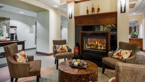 A lobby with a fireplace, seating area, and a coffee station.