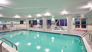 An indoor swimming pool with a checkered floor pattern, a lifeguard station, and lounge chairs.