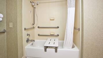 Une salle de bain équipée d’une baignoire, de barres d’appui, d’un pommeau de douche et d’un rideau de douche.