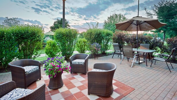 An outdoor patio area with wicker furniture, a checkered floor, and a table with chairs.