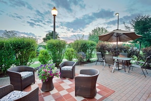 An outdoor patio area with wicker furniture, a checkered floor, and a table with chairs.