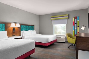 A hotel room with two beds, a desk, a chair, a window with blinds, a wall-mounted lamp, and a colorful abstract painting. - Hampton Inn Chicopee/Springfield (Chicopee)