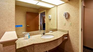 A bathroom with a granite countertop sink, a hand dryer, and a mirror.