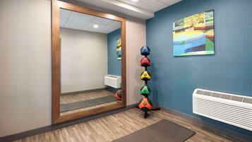 Una habitación con un espejo grande, aire acondicionado en la pared y un cuadro de colores.