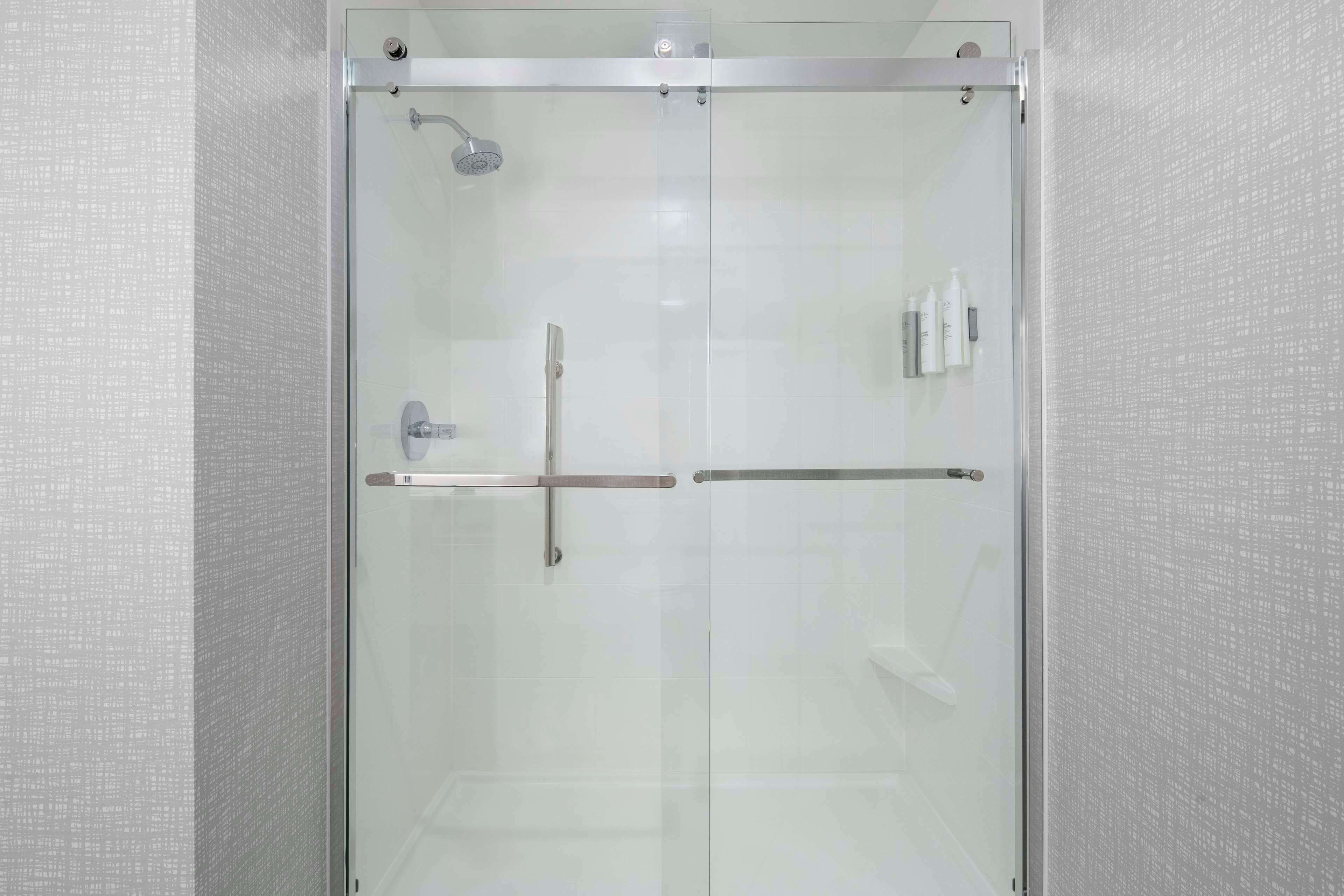 Ducha con cerramiento de vidrio, cabezal de ducha manual y grifo monomando.