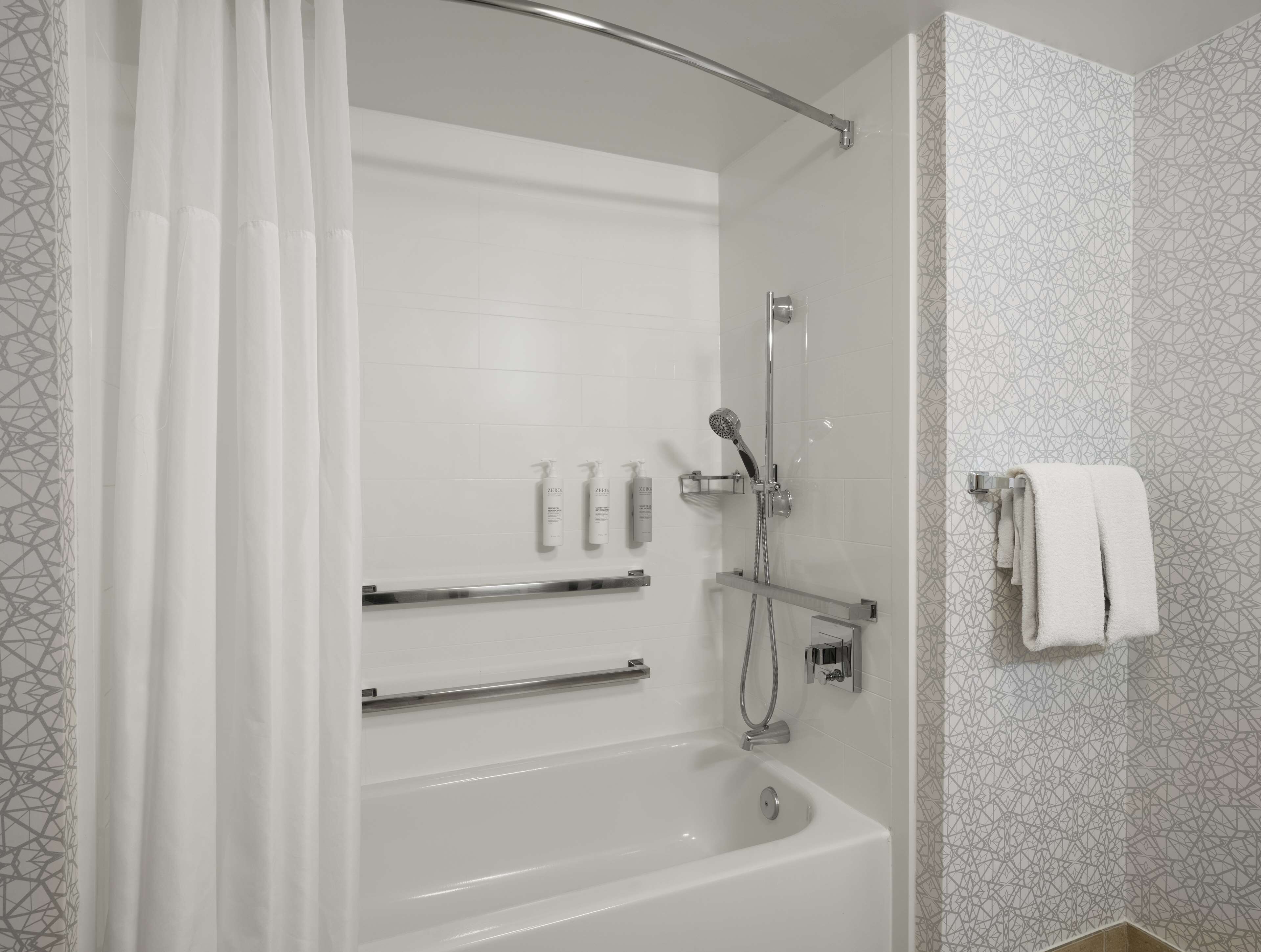 Un baño moderno con bañera, ducha y perchero para toallas.