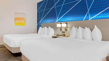 Een hotelkamer met twee bedden, een nachtkastje met een lamp, en een muur met een geometrisch patroon.