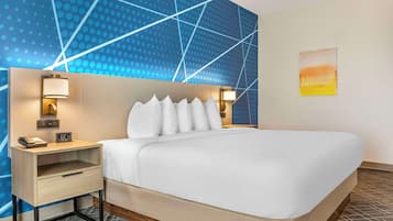 Una habitación de hotel con cama, mesitas de noche, un reloj de pared y un cuadro.