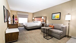 A hotel room with a bed, a sofa, a desk, and a lamp. - Hampton Inn & Suites Sacramento-Cal Expo (Sacramento)