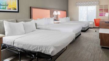 A hotel room with two beds, a desk, a chair, and a window with a view.