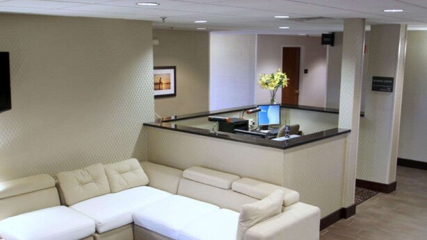 A hotel lobby with a large L-shaped sectional sofa, a reception desk, and a decorative vase with flowers. - Hampton Inn Williamston (Williamston)