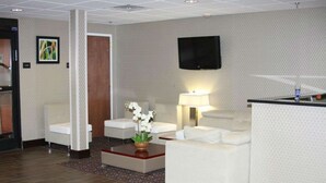 A hotel lobby with a reception desk, two white sofas, a coffee table with a flower arrangement, a TV mounted on the wall, and a patterned carpet. - Hampton Inn Williamston (Williamston)