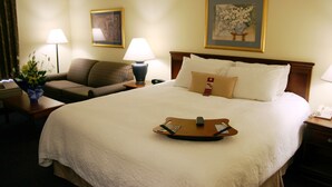 A hotel room with a large bed, two bedside tables, a chair, and two lamps. - Hampton Inn Williamston (Williamston)