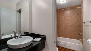 A bathroom with a white sink, mirror, and a shower area with a bathtub. - Motel 6 Ilion, NY (Ilion)