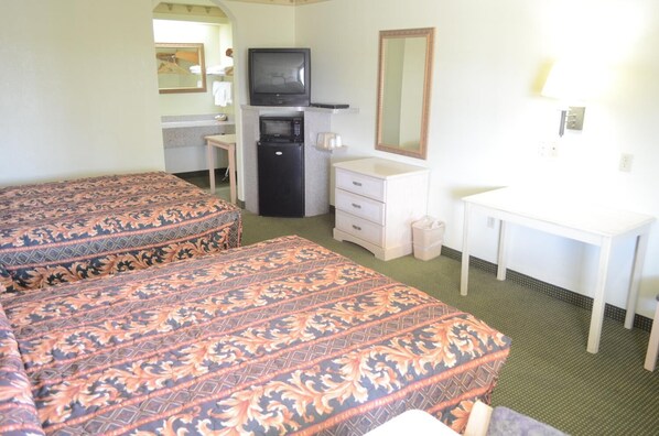 A hotel room with two beds, a television, a microwave, a small refrigerator, a desk, and a mirror. - Scottish Inns & Suites at NRG Park (Houston)