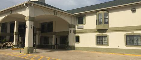 A building with a covered entrance, multiple windows, and a parking area with yellow lines.