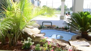 A swimming pool surrounded by tropical plants and a stone border. - Scottish Inns & Suites at NRG Park (Houston)