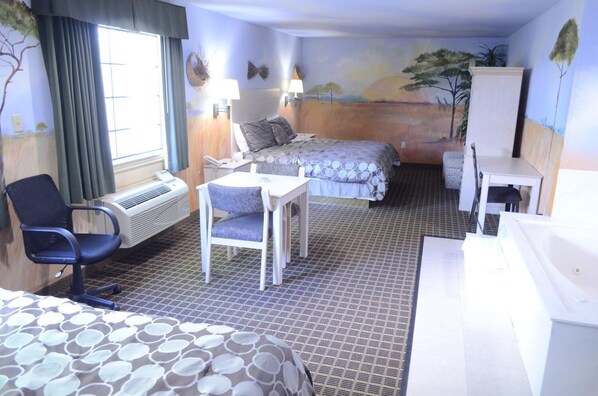 A hotel room with two beds, a desk, a chair, a window with curtains, a radiator, and a wall mural.