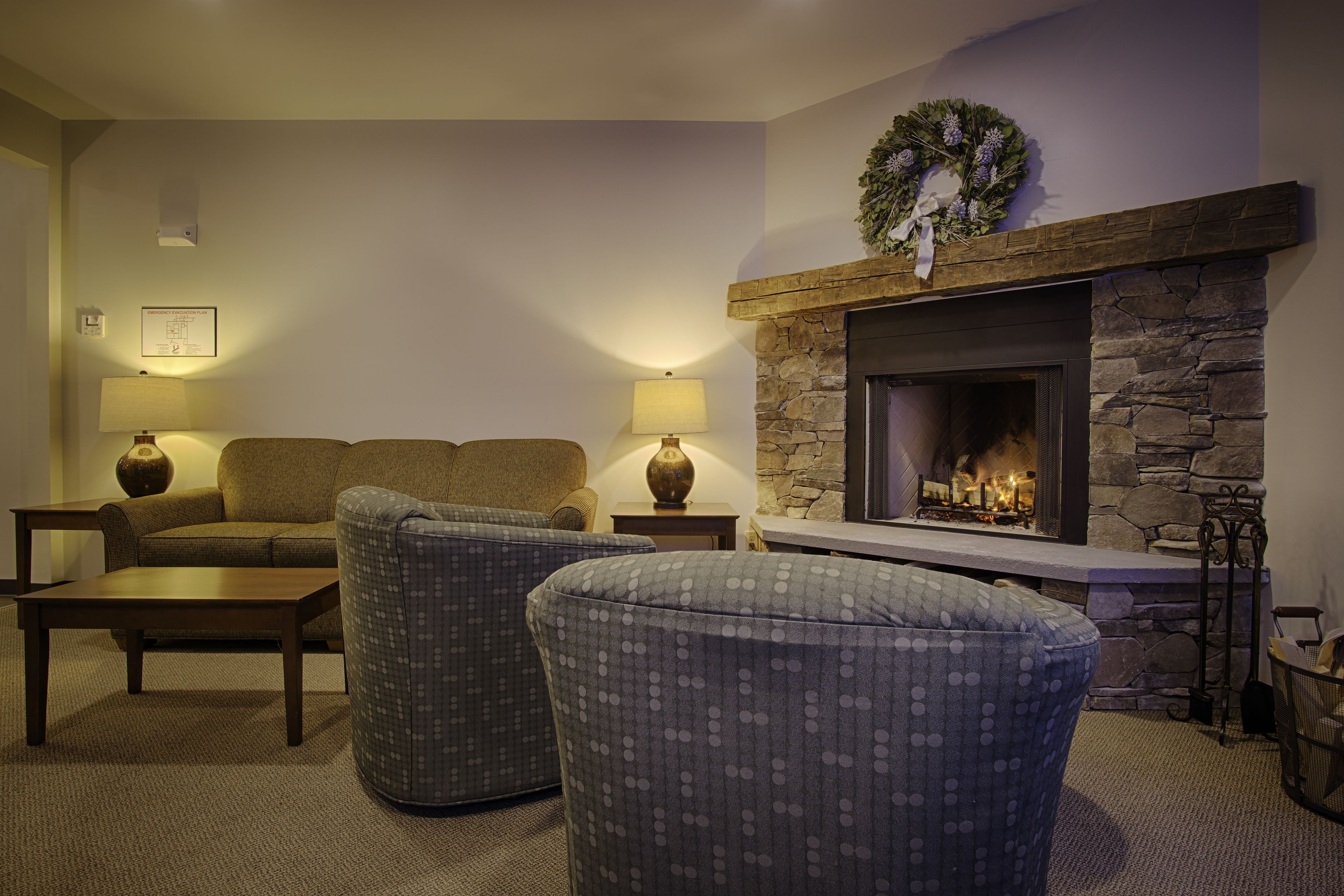 Ein gemütliches Wohnzimmer mit Kamin aus Stein, zwei Sofas und zwei Sesseln.