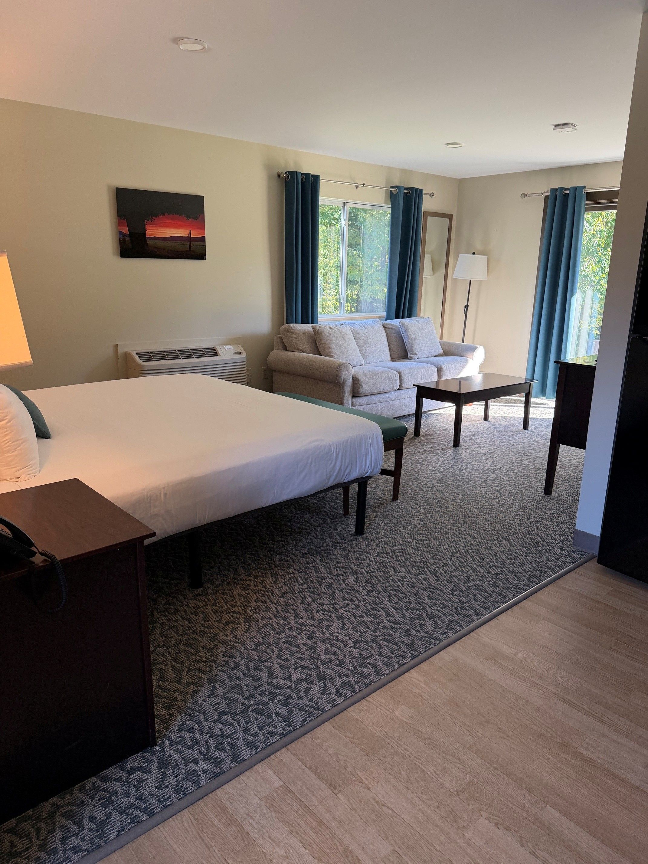 Una habitación de hotel con una cama, un sofá, una mesa y una lámpara.