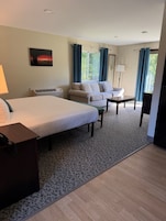Una habitación de hotel con una cama, un sofá, una mesa y una lámpara.