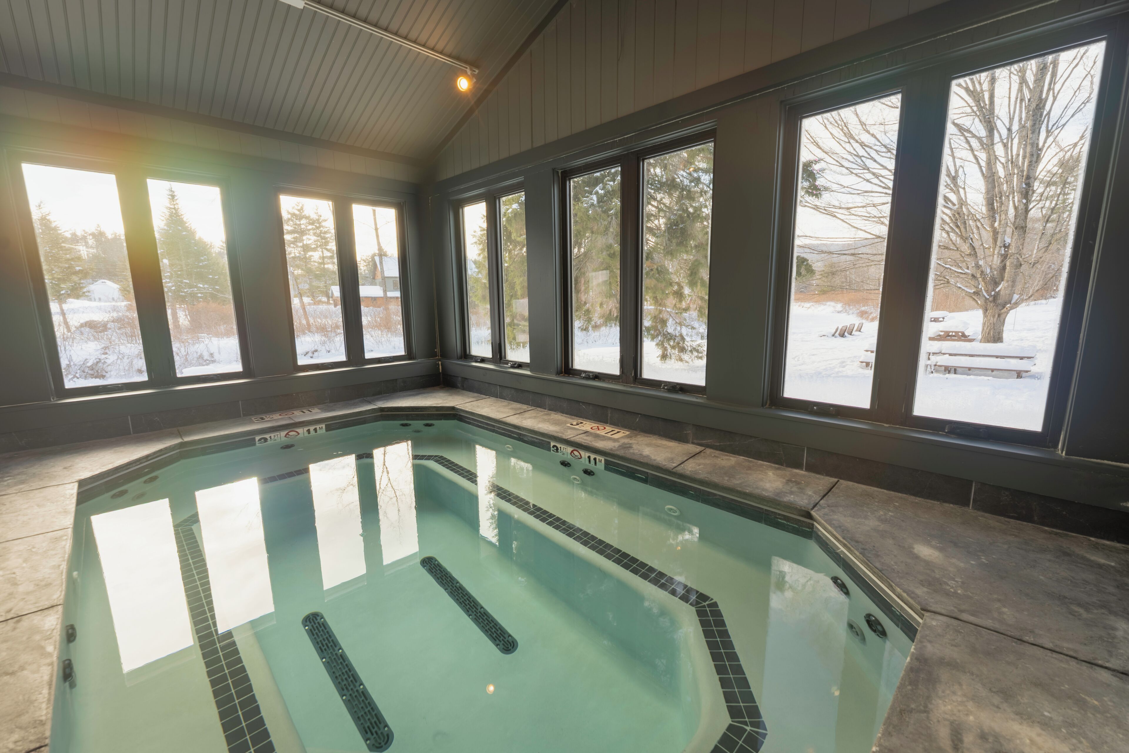 Ein Hallenbad mit freiem Blick auf eine verschneite Landschaft durch große Fenster.