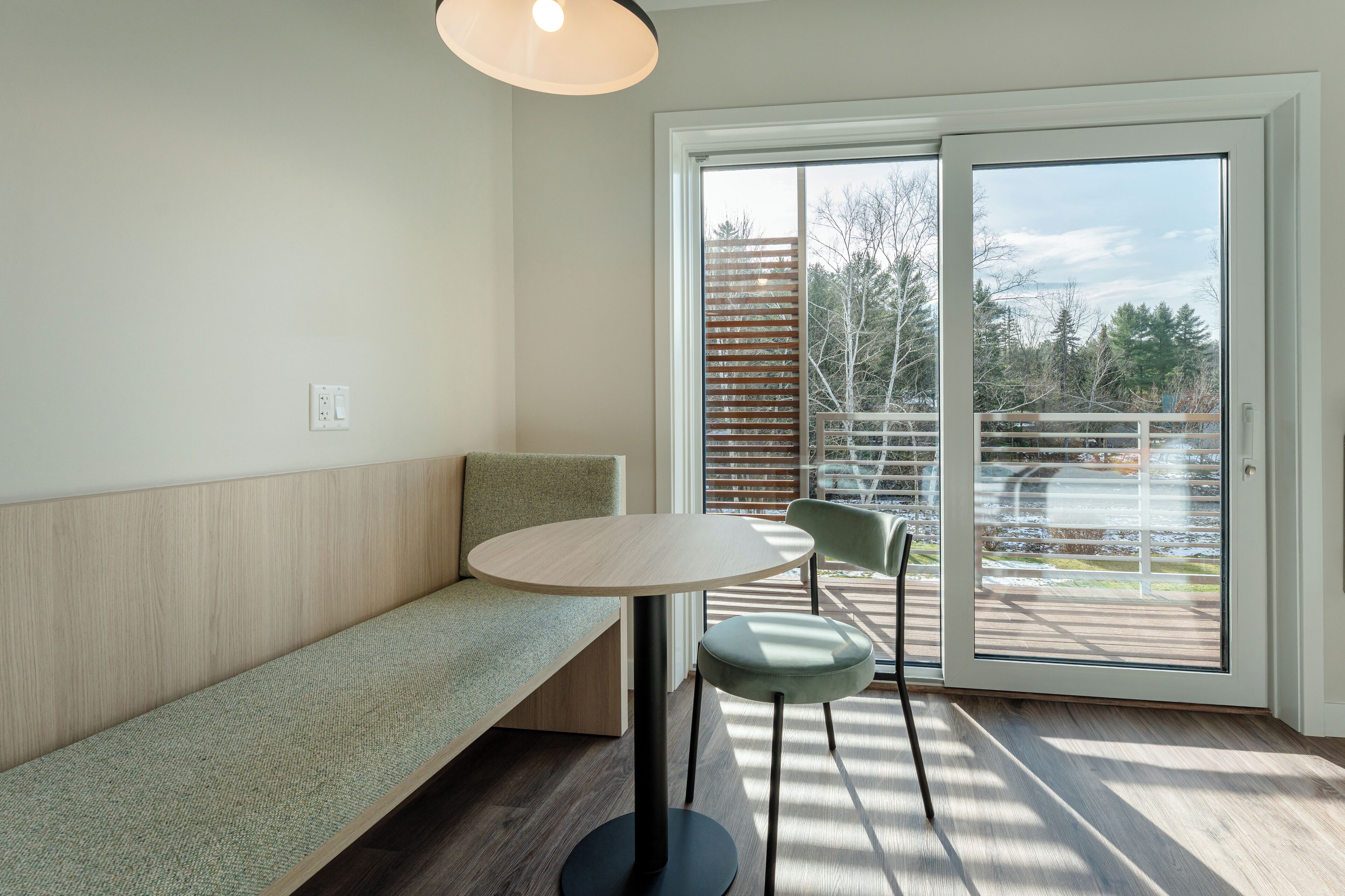 A modern room with a bench, a round table, and two chairs.