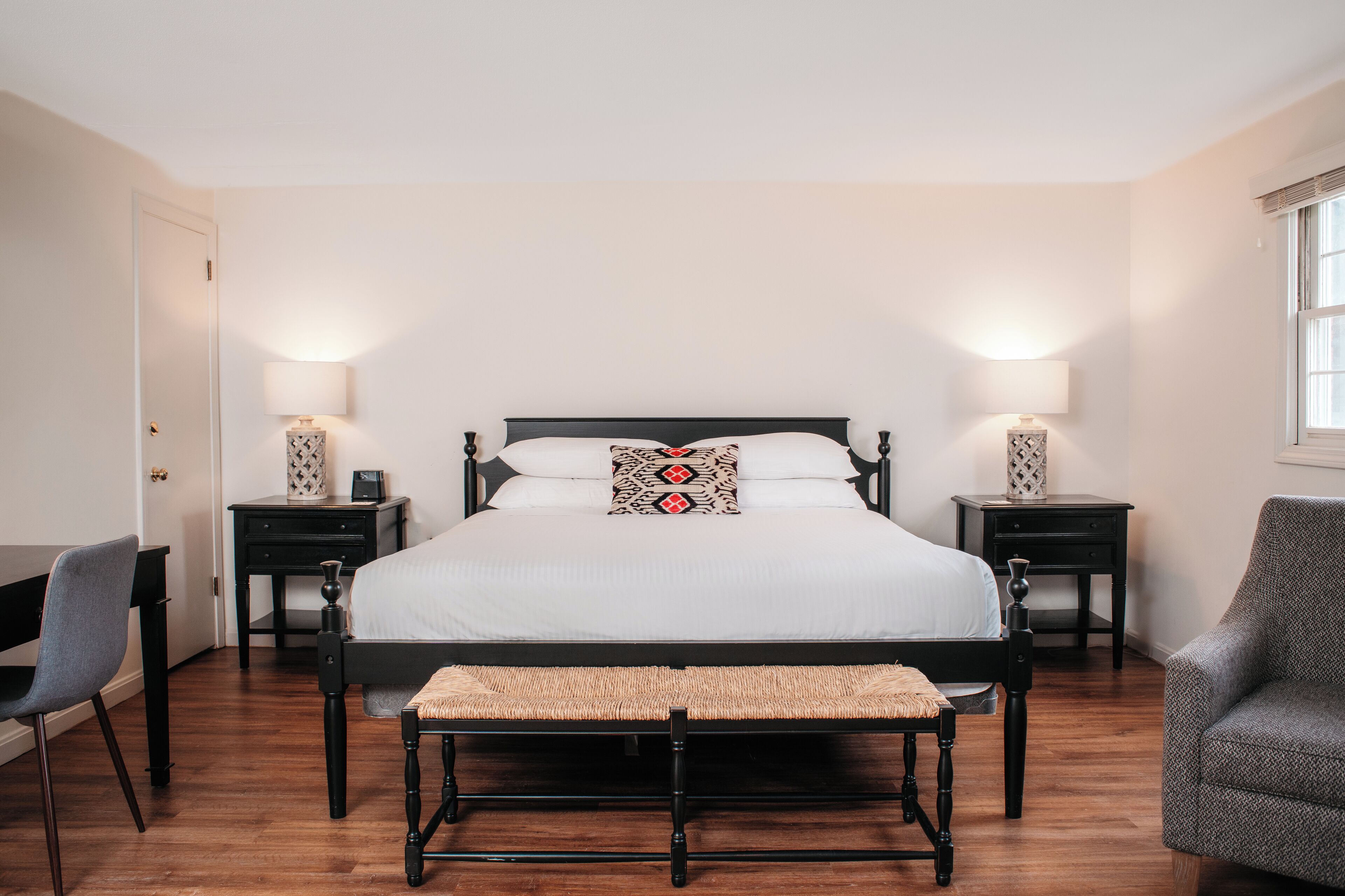 A neatly arranged bedroom with a large bed, bedside tables, a desk, and a chair.